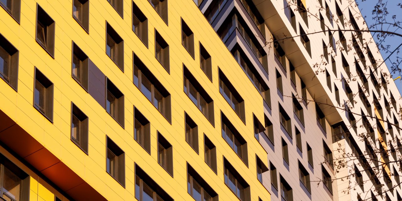 Yellow modern ventilated facade with windows. Part of urban real estate. Fragment of a new elite residential building or commercial complex.